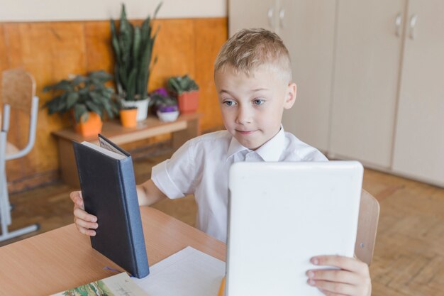 Boy choosing between textbook and tablet