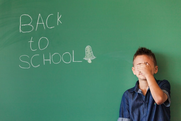 Free photo boy closing face in classroom