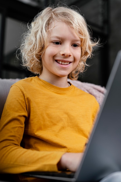 ラップトップとソファの上の少年