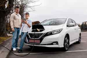 Foto gratuita ragazzo e papà vicino a un'auto elettrica