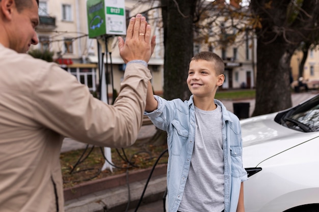 Foto gratuita ragazzo e papà vicino a un'auto elettrica