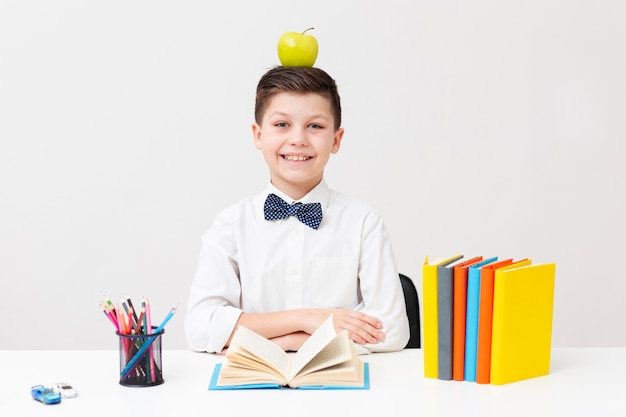 Free photo boy at desk with apple on head