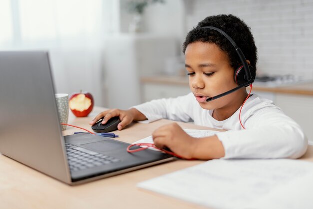 Boy doing homework with use of laptop