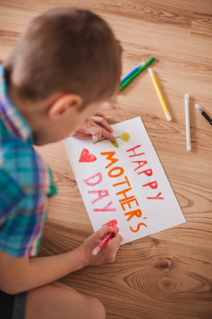 Boy drawing a poster for his mother