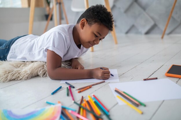 床に横たわって鉛筆で描く少年
