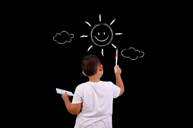 A boy draws the sky and the sun with a chalkboard