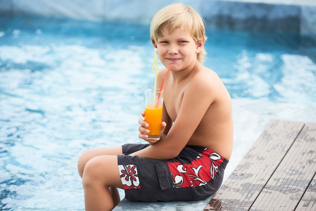 Boy drinking juice by the pool