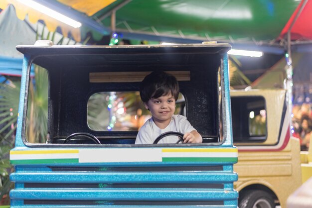 놀이 공원에서 장난감 트럭을 운전하는 소년