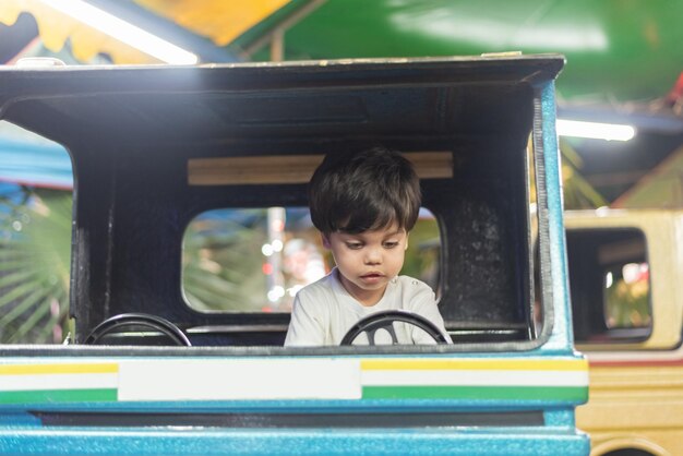 遊園地でおもちゃのトラックを運転する少年