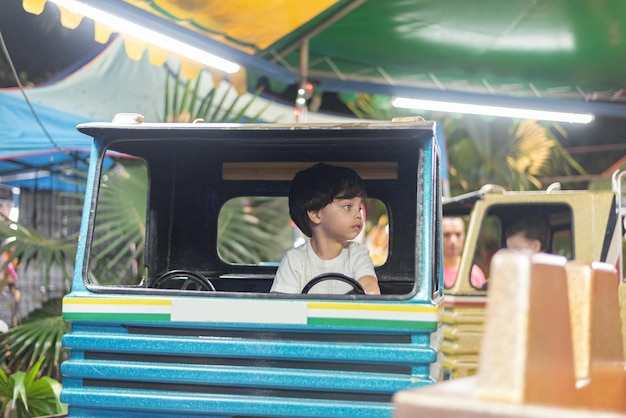 Мальчик за рулем игрушечного грузовика в парке развлечений