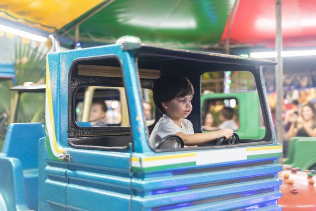 Мальчик за рулем игрушечного грузовика в парке развлечений
