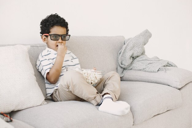 ポップコーンを食べる少年。ガラスの少年アフリカ人。子供向けの映画を見ています。