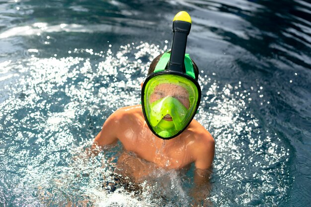 Мальчик наслаждается своим днем в бассейне с маской для подводного плавания