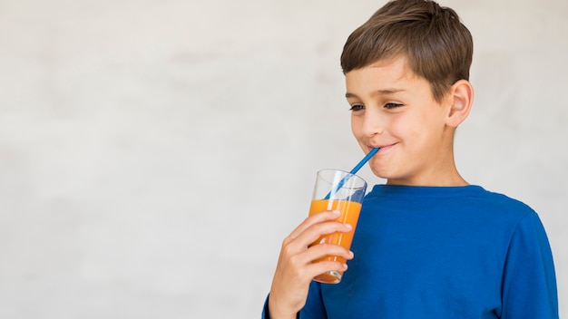 Free photo boy enjoying his orange juice with copy space