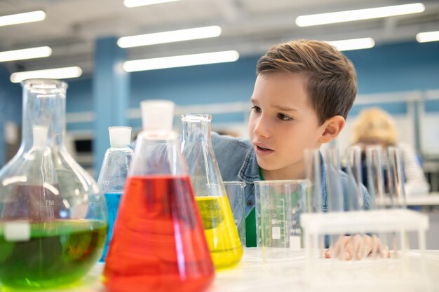 Boy examining flasks with colored liquids