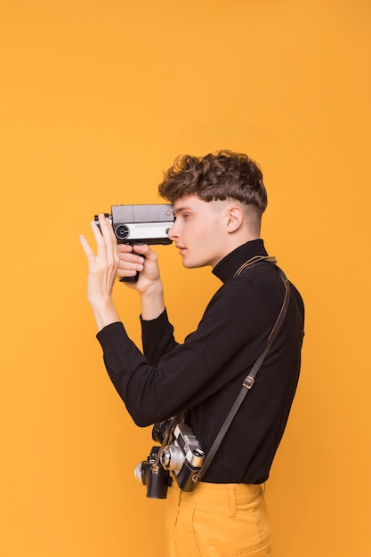 Free photo boy filming with a camcorder in a yellow scene