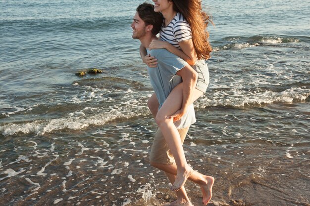 Boy friend carrying girlfriend at the shoreline