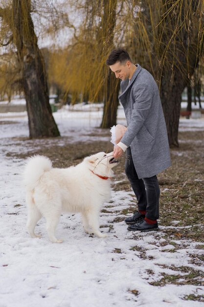 Ragazzo amico con un mazzo di fiori rosa ortensia in attesa della sua ragazza all'aperto mentre la neve sta cadendo. concetto di san valentino, proposta di matrimonio. l'uomo va ad un appuntamento.