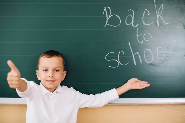 Boy gesturing at blackboard in class