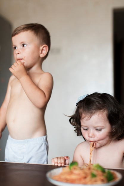Мальчик и девочка едят макароны