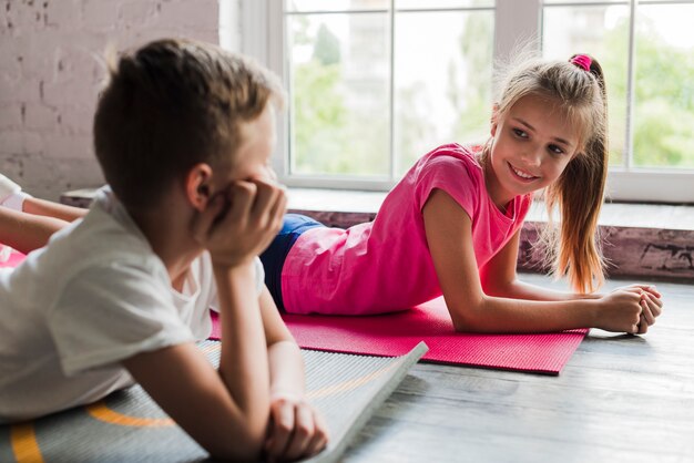 男の子と女の子がお互いを見て運動マットの上に横たわる