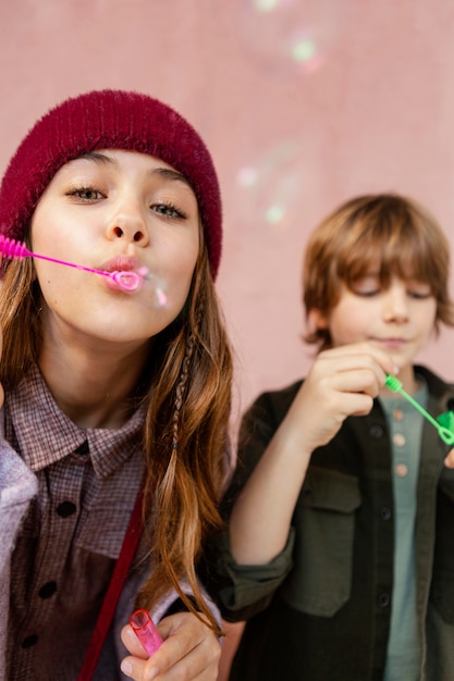 Free photo boy and girl playing with soap bubbles