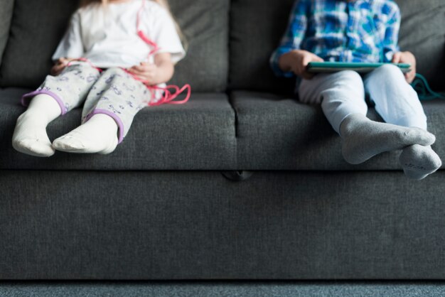 Boy and girl sitting on couch looking at tablet