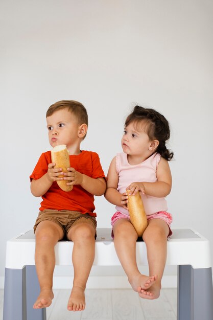 Boy and girl sitting on a table and eating bread