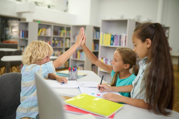 Boy and girl touching raised hand sitting opposite each other