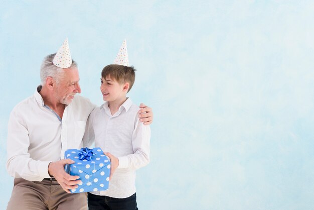 Boy giving blue gift box to his grandfather on his birthday