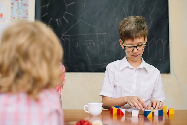 Boy in glasses sitting at table playing