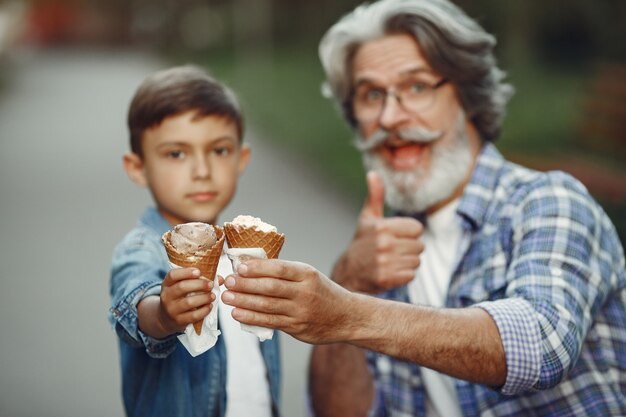 Мальчик и дедушка гуляют по парку. Старик играет с внуком. Семья с мороженым.