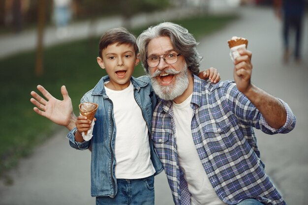 少年と祖父が公園を歩いています。老人が孫と遊んで。アイスクリームと家族。