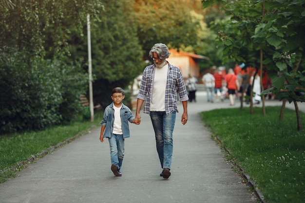 Free photo boy and grandfather are walking in the park. old man playing with grandson.