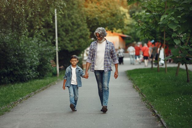 Boy and grandfather are walking in the park. Old man playing with grandson.