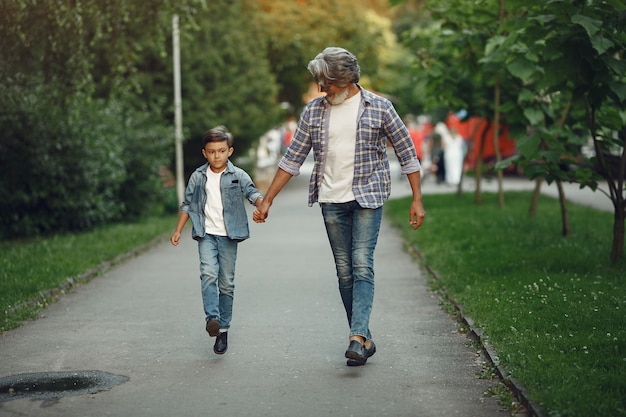 Boy and grandfather are walking in the park. Old man playing with grandson.