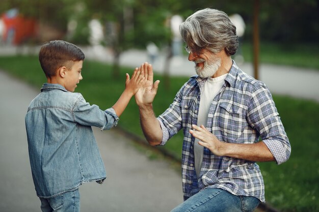 Boy and grandfather are walking in the park. Old man playing with grandson.