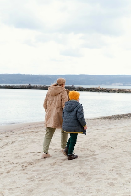 Мальчик и бабушка на пляже, полный выстрел