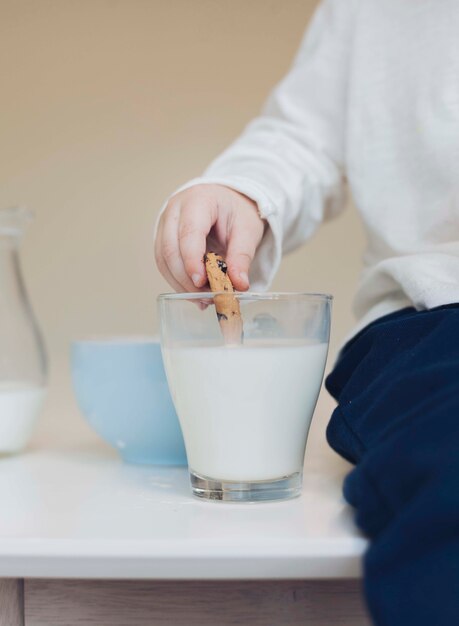 男の子の手が牛乳にクッキーを浸す