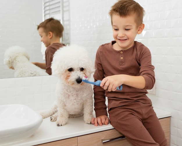 Мальчик помогает своей собаке мыть зубы дома