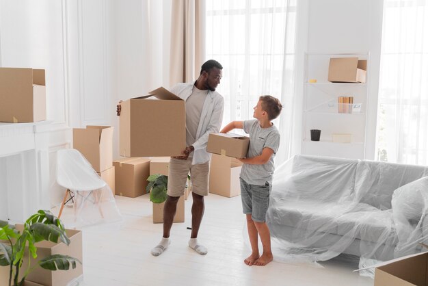 Boy helping his father to carry packages for moving out