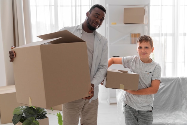 Free photo boy helping his father to carry packages for moving out