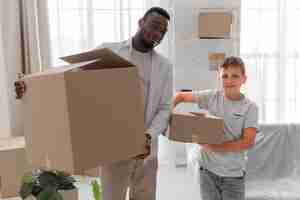 Free photo boy helping his father to carry packages for moving out