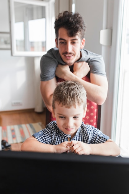 Foto gratuita ragazzo e suo padre guardando portatile