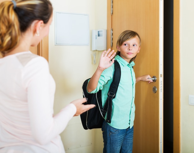 Boy and his mother staying near flat entrance 