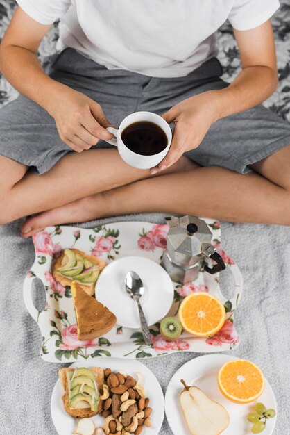 A boy holding black coffee cup in his hand having healthy breakfast