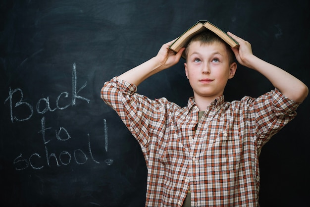 Free photo boy holding book over head looking up