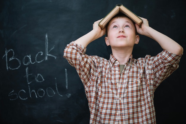 Free photo boy holding book over head