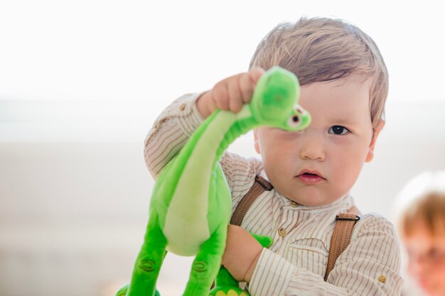 Boy holding dinosaur toy looking at camera