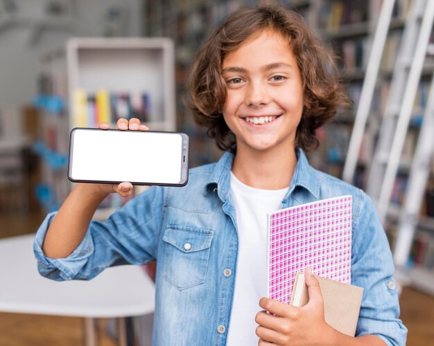 図書館で空の画面の電話を持っている少年